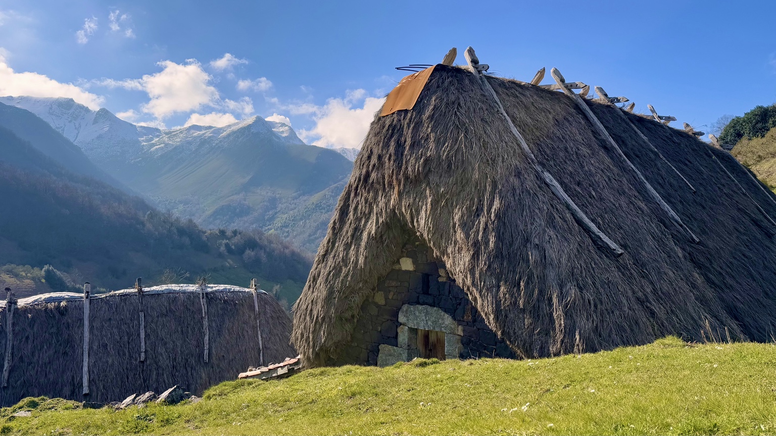 Teito de la Braña de La Pornacal con las montañas nevadas de Somiedo al fondo